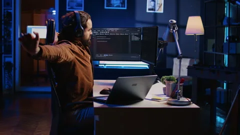 Programmer taking break from coding, putting headphones on and stretching Stock Footage 265620952