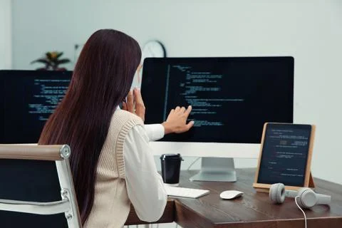 Programmer talking on phone while working at desk in office Foto stock