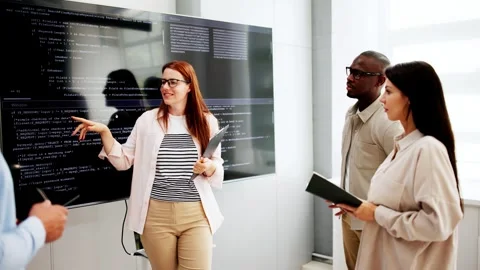 Programmer Team Meeting With TV Screen In Office Stock Footage 281299980