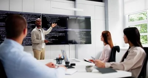 Programmer Team Meeting With TV Screen In Office. Diverse Developers Foto stock