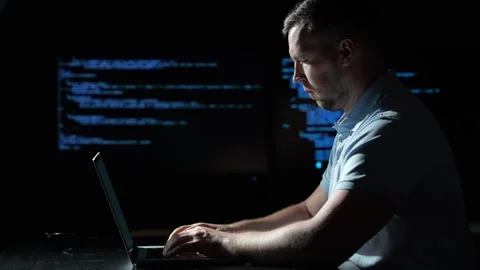 Programmer types code on laptop. Focused programmer works beside multiple code Stock Footage 342648136