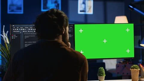 Programmer typing complex code on green screen computer in neon lit home office 写真素材