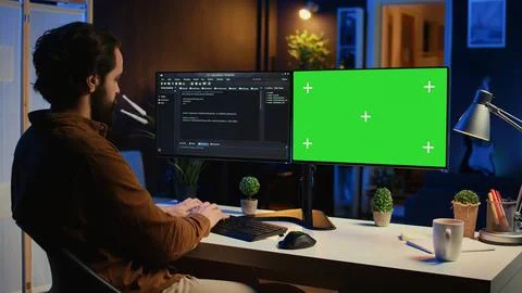 Programmer typing complex code on green screen computer in neon lit home office Stock-Fotos