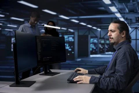 Programmer typing on PC in data center, updating systems Foto stock