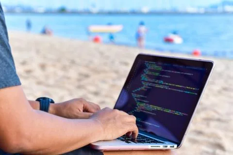 A programmer typing source codes at the beach on a sunny summer day. Studying Stock Photos