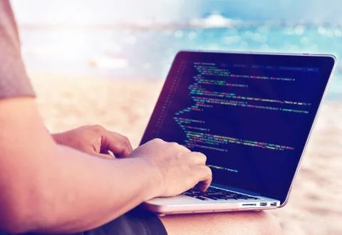 A programmer typing source codes at the beach on a sunny summer day. Studying Stock Photos