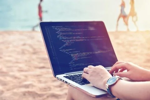 A programmer typing source codes at the beach in a relaxing working environme Stock Photos