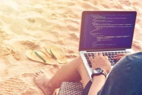 A programmer typing source codes at the beach in a relaxing working environme 写真素材