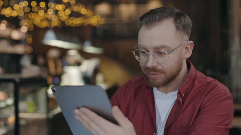 Programmer typing at tablet while working at cafe. Man using gadget with smile. Stock Footage 170545384