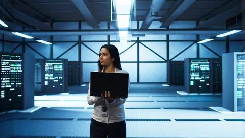 Programmer walking in data center, coding on laptop Stock-Fotos