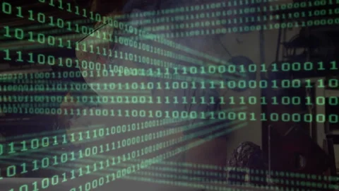 Programmer wearing glasses coding at desk under binary code overlay, showing Stock Footage 308100979