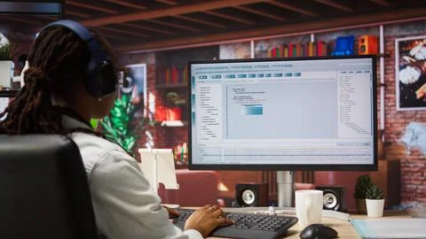 Programmer wearing headphones types code into PC, developing software Stock Photos