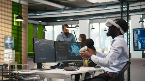 Programmer wearing VR headset at office desk developing programs using AI Stock Footage 313017351