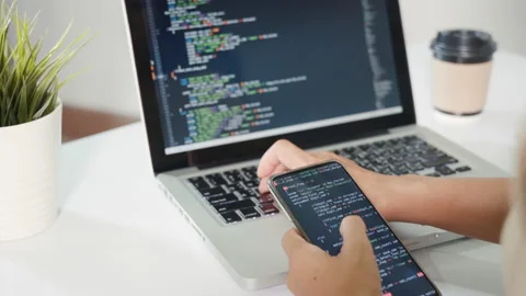 Programmer woman looking mobile phone program code at workplace Stock Footage 233589323
