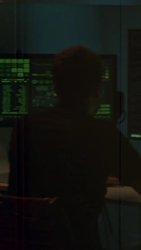 Programmer at work coding session, focused on multiple screens displaying green Stock Footage 323743625