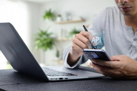 Programmer Working on API Development with Laptop and Smartphone Foto stock