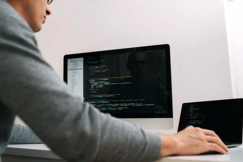 Programmer, working behind the desk, analysing code on the black screen. 库存照片