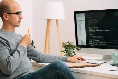 Programmer, working behind the desk, analysing code on the black screen. Stock Photos
