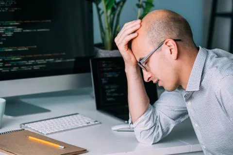 Programmer, working behind the desk, analysing code on the black screen. Foto stock