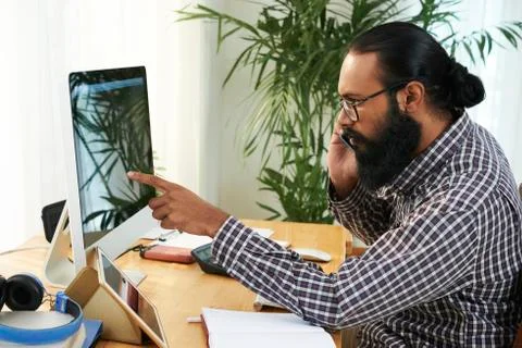 Programmer working on computer and talking on the phone Stock Photos