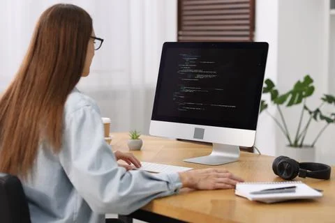 Programmer working on computer at wooden desk indoors 스톡 사진