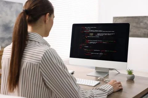 Programmer working on computer at wooden desk indoors, back view Stock Photos