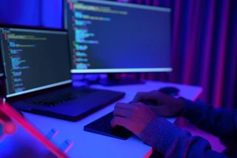 Programmer Working at Dual Monitors in Neon Lit Office Fotos Stock