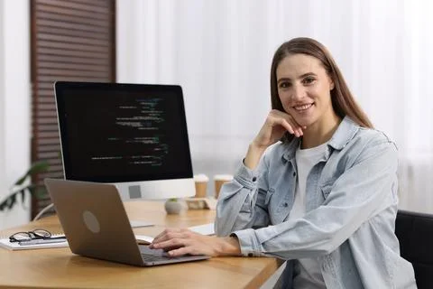 Programmer working on laptop and computer at wooden desk indoors Foto stock