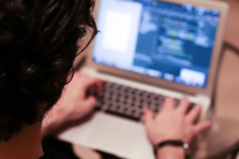 Programmer working on laptop computer in office. Real software program code o Stock Photos