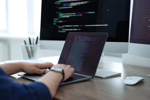 Programmer working with laptop at desk in office, closeup 写真素材
