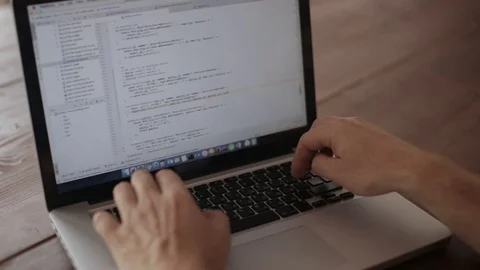 The programmer working on laptop, sitting at a wooden table Stock Footage 124652950