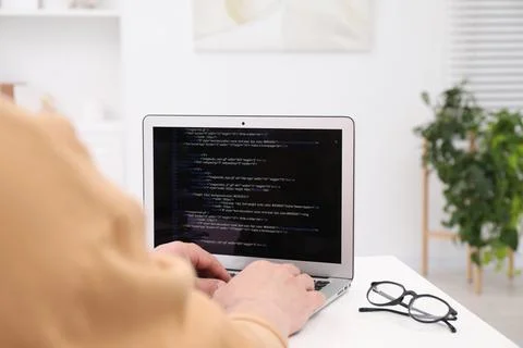 Programmer working with laptop at white desk in office, closeup Stock Photos