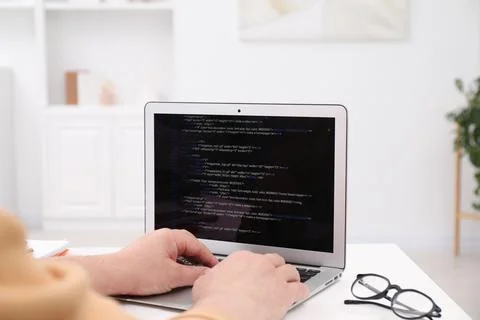 Programmer working with laptop at white desk in office, closeup Stock Photos