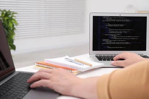 Programmer working with laptop at white desk in office, closeup Stock Photos