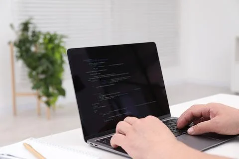 Programmer working with laptop at white desk in office, closeup Stock Photos