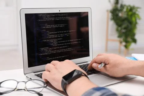 Programmer working with laptop at white desk in office, closeup Stock Photos