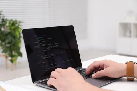 Programmer working with laptop at white desk in office, closeup Stock Photos