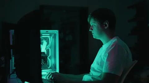 Programmer working late, illuminated by computer screen, intently coding or Video stock 317535909