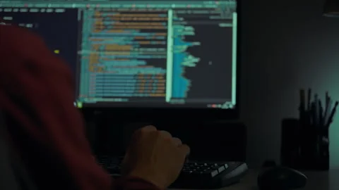 A programmer working late at night coding on a computer in a dimly lit works Stock Footage 288633987