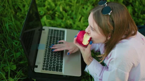 Programmer Working Outdoors on Laptop with Apple in Hand Stock Footage 301697267
