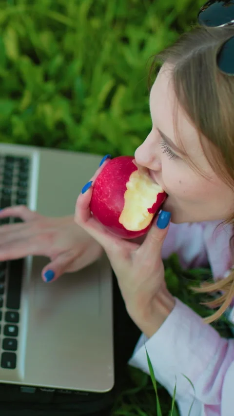 Programmer Working Outdoors on Laptop with Apple in Hand 스톡 동영상 317579265