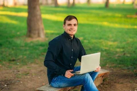 Programmer working in the park on laptop. Man sitting on bench 写真素材
