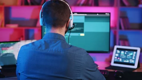 Programmer is working by sitting by computer. Neon lighting. Stock Footage 245361064