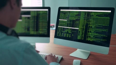 Programmer working with two computer screens showing code Video stock 294079230
