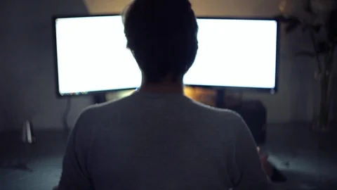 The programmer works behind two monitors at night, rear view. Stock Footage 118639047
