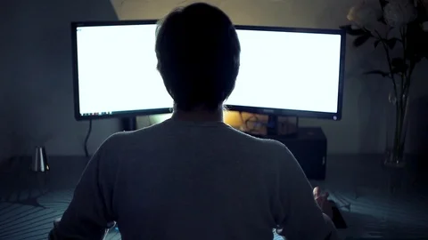 The programmer works behind two monitors at night, rear view. Stock Footage 118696372