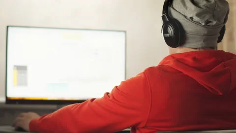 A programmer in a works in a home office in the sitting at a monitor screen 스톡 동영상 153944734