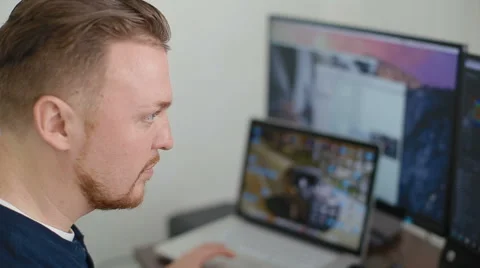 The programmer works with a serious look behind monitors Stock Footage 62519076