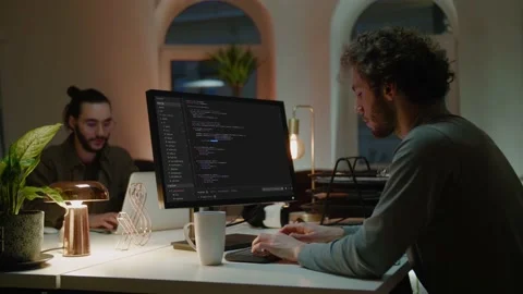 Programmer writes code on computer at table near colleague Video stock 150396711