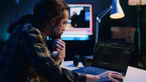 Programmer writes code on laptop screen while in apartment office using Java Stock Photos